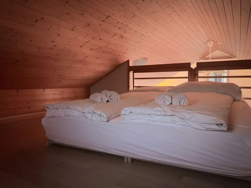 Warm, inviting loft bedroom featuring wooden ceiling and fresh linens.